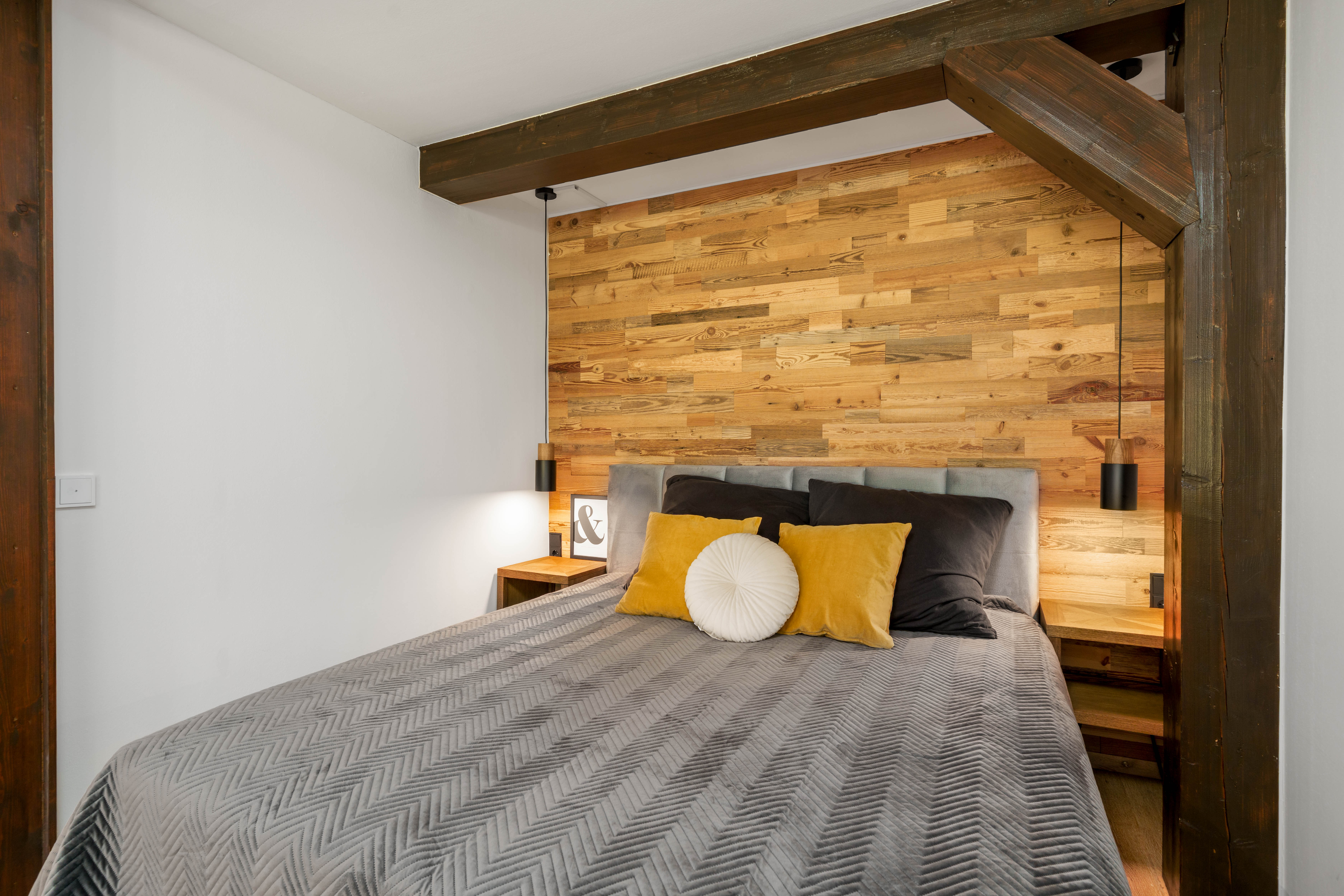 Schlafbereich mit Boxspring-Bett und Altholz-Rückwand